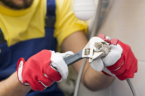 Workplace Safety Gloves and Masks plumber screwing plumbing fittings in bathroom